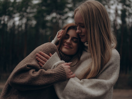 Close-up emotional portrait of young lesbian couple hugging tightly, smiling with closed eyes. Showing mutual support, tenderness, trust, and deep emotional bond in diverse LGBT relationships.の写真素材