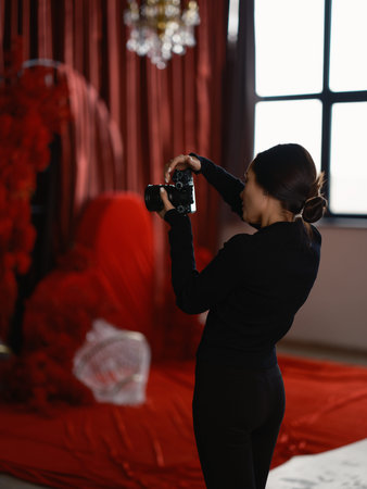 Back view of professional woman photographer with camera taking photos of big red heart decoration....