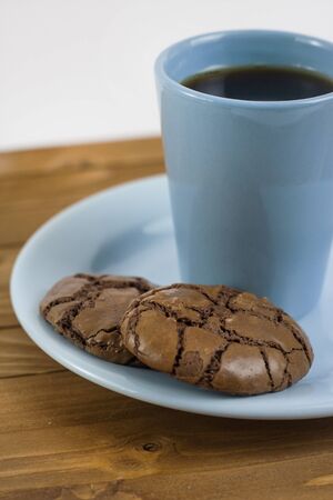 Black Brownie Cookies and blue coffee mug on a wooden tableの写真素材