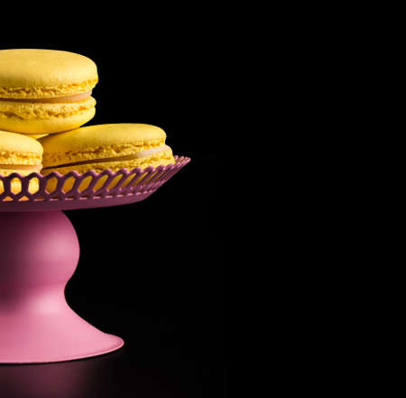 Yellow Macarons on a black background French pasta. Stack of yellow macaron with isolated on dark, black background. Macaroons.の写真素材