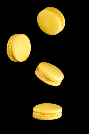 Yellow Macarons on a black background. French pasta. Stack of yellow macaron with isolated on dark, black background. Macaroons.の写真素材