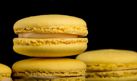 Yellow Macarons on a black background French pasta. Stack of yellow macarons isolated on dark, black background. Macaroonsの写真素材