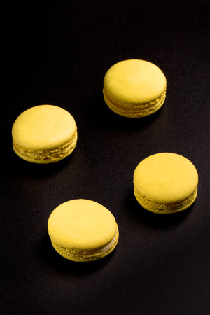 Yellow Macarons on a black background French pasta. Stack of yellow macarons isolated on dark, black background. Macaroonsの写真素材