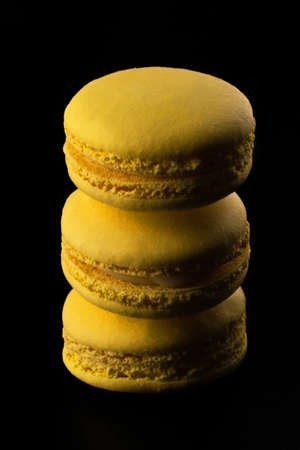 Yellow Macarons on a black background French pasta. Stack of yellow macarons isolated on dark, black background. Macaroonsの写真素材