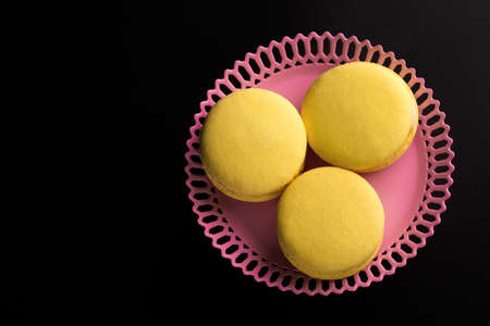 Yellow Macarons on a black background French pasta. Stack of yellow macaron with isolated on dark, black background. Macaroons.の写真素材