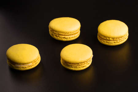 Yellow Macarons on a black background French pasta. Stack of yellow macaron with isolated on dark, black background. Macaroons.の写真素材