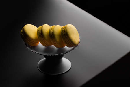 Yellow Macarons on a black background French pasta. Stack of yellow macaron with isolated on dark, black background. Macaroons.の写真素材