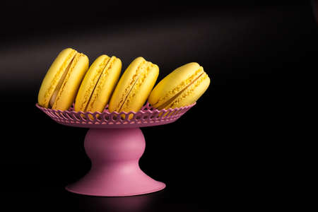 Yellow Macarons on a black background French pasta. Stack of yellow macaron with isolated on dark, black background. Macaroons.の写真素材