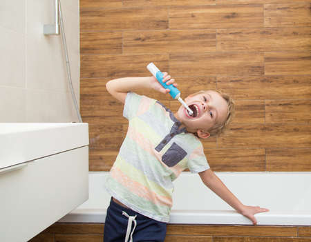 A five-year-old boy is brushing his teeth in the bathroom. A five-year-old boy, a European on the street, brushes his teeth in the bathroom in front of the mirror.の写真素材