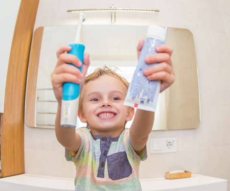 A five-year-old boy is brushing his teeth in the bathroom. A five-year-old boy, a European on the street, brushes his teeth in the bathroom in front of the mirror.の写真素材