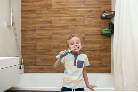 A five-year-old boy is brushing his teeth in the bathroom. A five-year-old boy, a European on the street, brushes his teeth in the bathroom in front of the mirror.の写真素材