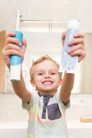 A five-year-old boy is brushing his teeth in the bathroom. A five-year-old boy, a European on the street, brushes his teeth in the bathroom in front of the mirror.の写真素材