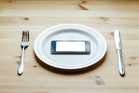 man's hand with a fork and knife cut smartphoneの写真素材