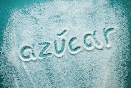 word sugar written in Spanish into a pile of white granulated sugarの写真素材