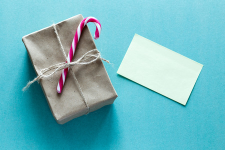 A paper parcel wrapped tied with a tag and candy cane. A christmas gift box wrapped with paper kraft and yellow blank paperの写真素材
