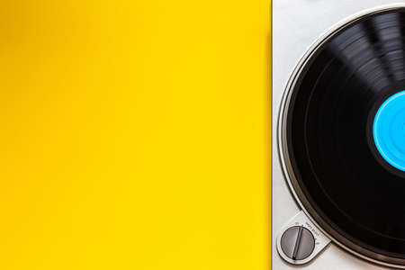 flat lay vinyl turntable with spinning lp record. blue label and yellow background and place for...