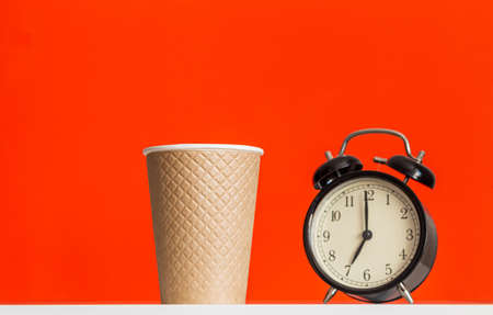 time to drink coffee, textured paper cup and alarm clock on red backgroundの写真素材