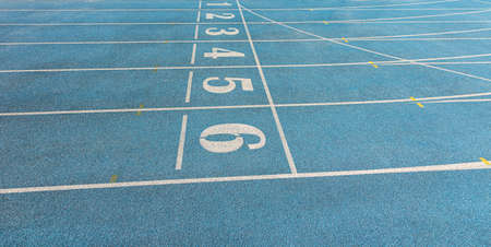 white numbers at the blue running track start line