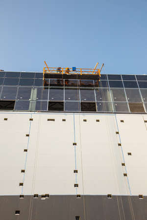 Workers on the aerial work platform at facade installation work