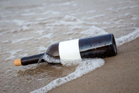a message in a bottle washed ashore by a waveの写真素材