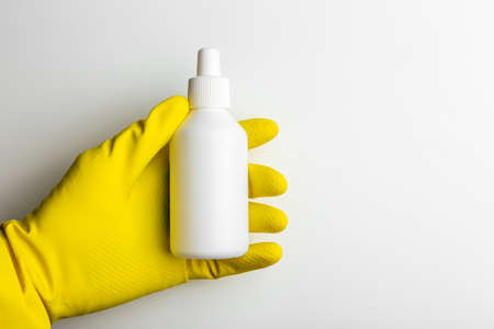 a hand in a rubber glove holds an blank white containerの写真素材