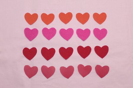 Colored hearts lie on a pink background.の写真素材