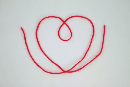 Heart made of red thread on a white background.の写真素材