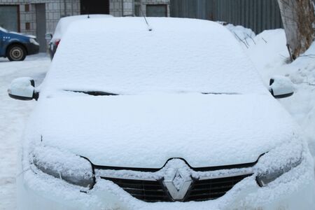 Car in modern style on white background with snow on glass. Winter background. Snowy white texture. Christmas snow. Front view.の写真素材