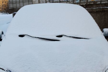 Car in modern style on white background with snow on glass. Winter background. Snowy white texture. Christmas snow. Front view.の写真素材
