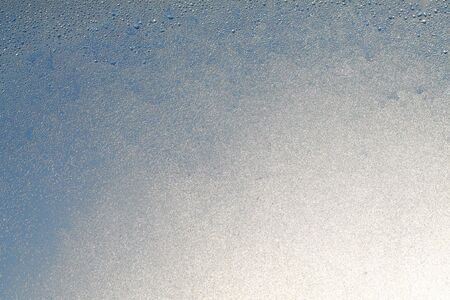 Blue window glass covered hoarfrost ice pattern texture. Cold nature winter background.の写真素材