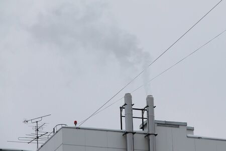 From two chimneys on the roof of the house comes smoke against the sky.の写真素材
