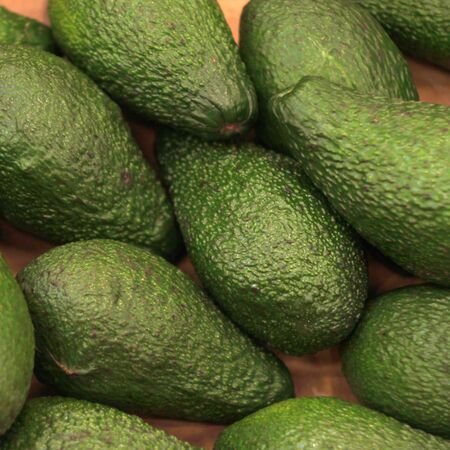 Green juicy avocado lie on a store counter.