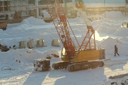 Large crawler crane works at a construction site on a frosty sunny day in winter in Russia.の写真素材