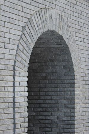 Brick gray wall with a semicircular arch entrance. Rough cement texture. Stock photo for web, print, background and wallpaper with empty space for text.の写真素材