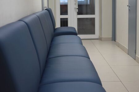 Leather black sofa in an empty long corridor with doors. Concept of office furniture. Stock photo for web and print with empty space for text. Concept of office furniture.の写真素材