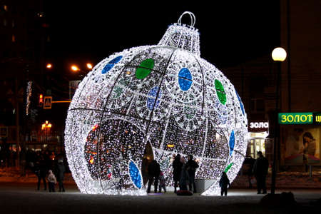 14 december 2019, Russia, Syktyvkar. Christmas light design in the form of a giant round Christmas tree toy with blue and green accents at night in the city. New Years festive cityscape with people and illumination.のeditorial素材
