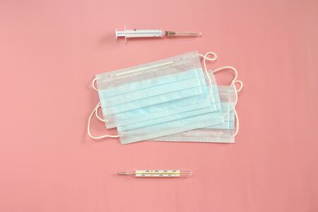 Medical disposable masks, thermometer and syringe on a pink background. Coronovirus Outbreak Defense Concept.の写真素材