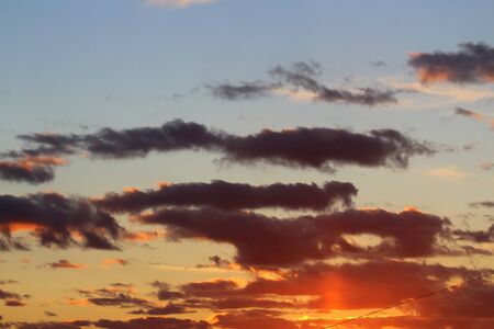 Clouds in the blue sky at sunset or dawn backlit by the sun. Place for text and design.の写真素材