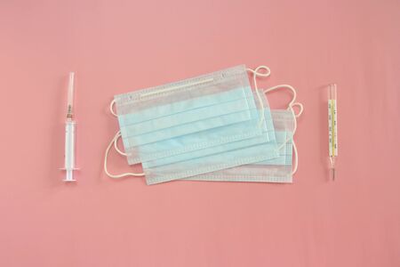 Medical disposable masks, thermometer and syringe on a pink background. Coronovirus Outbreak Defense Concept.の写真素材