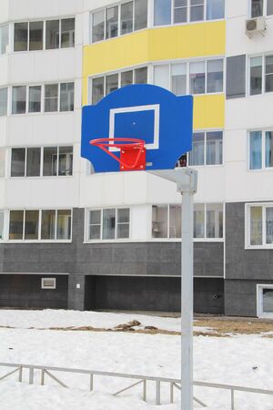 Red basketball hoop on a blue backboard on a sports field on a street in the city.の写真素材