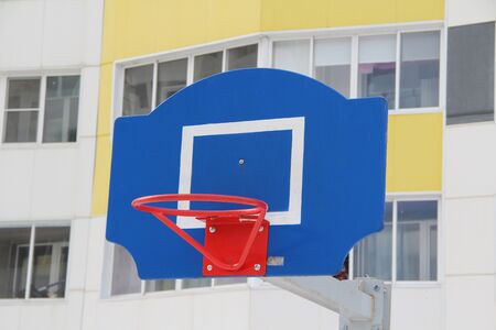 Red basketball hoop on a blue backboard on a sports field on a street in the city.の写真素材