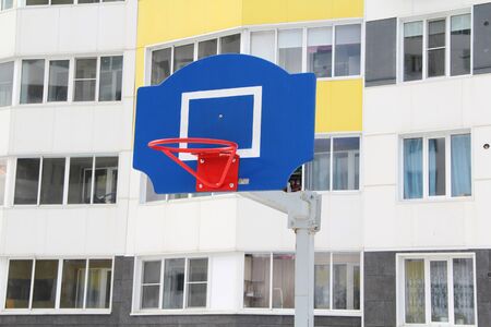 Red basketball hoop on a blue backboard on a sports field on a street in the city.の写真素材