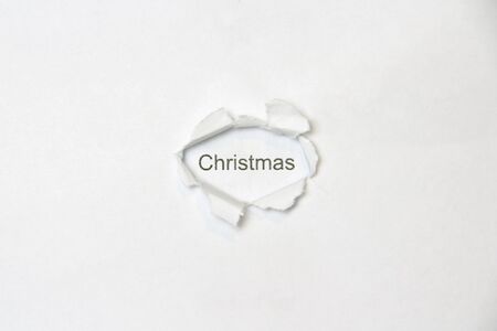 Word christmas on white isolated background, the inscription through the wound hole in the paper. Stock photo for web and print with empty space for text and design.の写真素材
