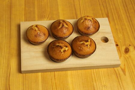 Five golden pies on a wooden board on a wooden table from boards.の写真素材