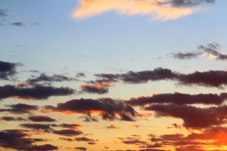 Clouds in the blue sky at sunset or dawn backlit by the sun. Place for text and design.の写真素材