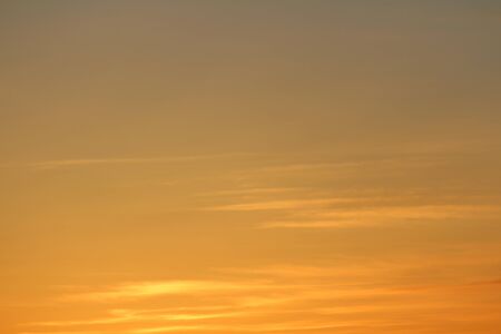 Sun below the horizon and clouds in the fiery dramatic orange sky at sunset or dawn backlit by the sun. Place for text and design.の写真素材
