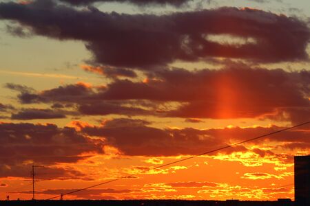 Sun below the horizon and clouds in the fiery dramatic orange sky at sunset or dawn backlit by the sun. Place for text and design.の写真素材