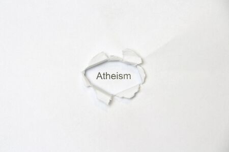 Word atheism on white isolated background, the inscription through the wound hole in the paper. Stock photo for web and print with empty space for text and design.の写真素材