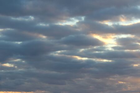 The suns rays pass through the dark clouds. Beautiful dramatic sky at sunset or sunrise.の写真素材