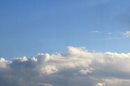 Clouds in the blue sky at sunset or dawn backlit by the sun. Place for text and design.の写真素材